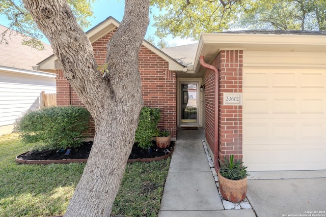 view of exterior entry with brick siding and an attached garage