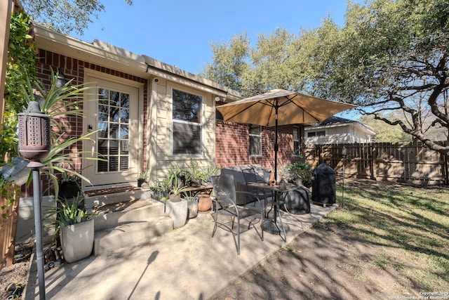 view of patio featuring entry steps, fence, and a grill