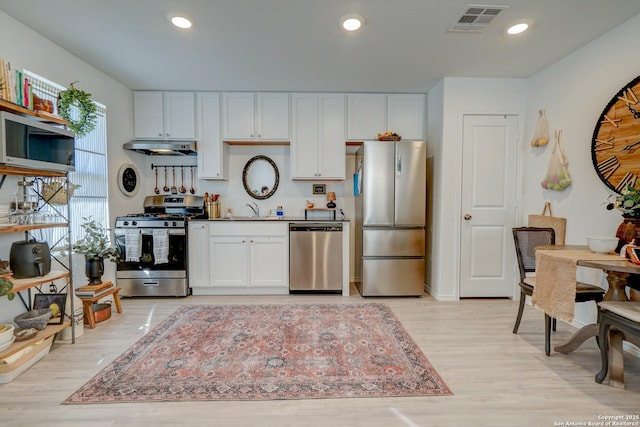 kitchen with visible vents, light wood-style floors, stainless steel appliances, under cabinet range hood, and white cabinetry