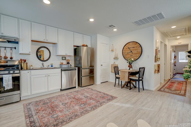 kitchen featuring light wood finished floors, visible vents, stainless steel appliances, and a sink