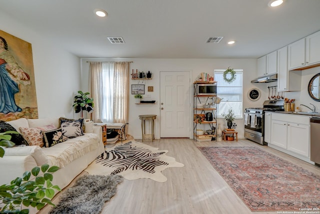 living area with light wood-type flooring, visible vents, and recessed lighting