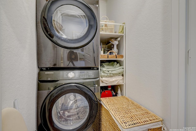 laundry room featuring a textured wall, laundry area, and stacked washing maching and dryer