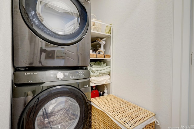 clothes washing area featuring stacked washer / drying machine, laundry area, and a textured wall