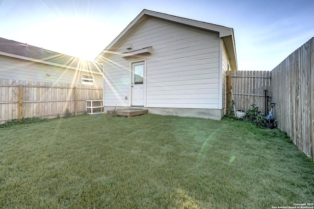 rear view of property featuring a fenced backyard and a yard