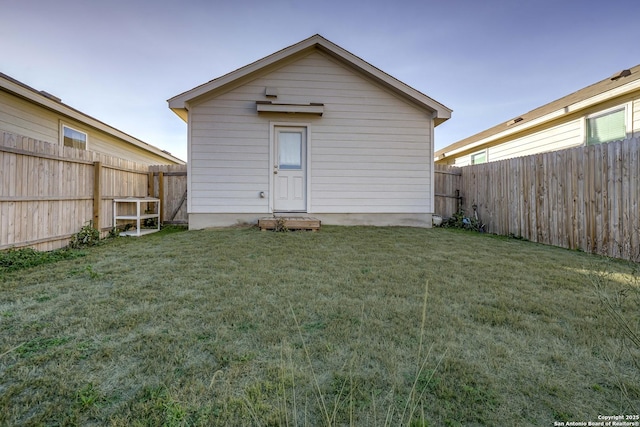 rear view of house with a fenced backyard and a yard