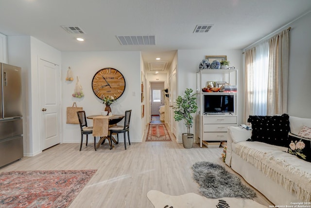 living area featuring light wood-style flooring, visible vents, and baseboards