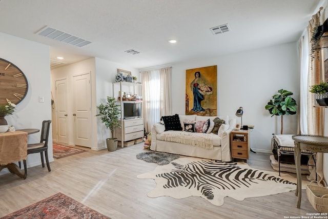 living area featuring light wood-type flooring, visible vents, and baseboards