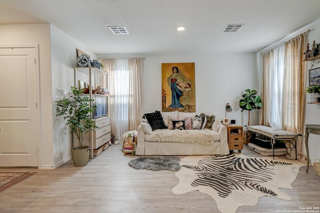 sitting room featuring a healthy amount of sunlight, visible vents, and wood finished floors