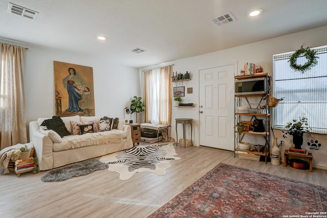 living room with a wealth of natural light, visible vents, and wood finished floors