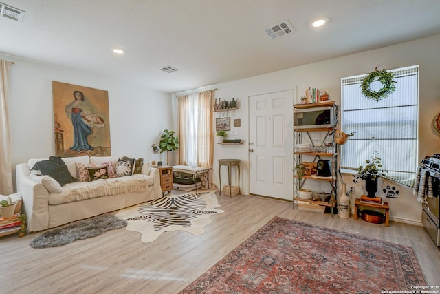 living area with wood finished floors, visible vents, and recessed lighting