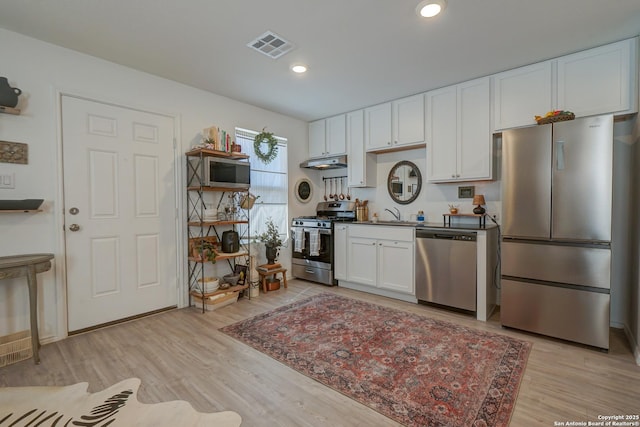 kitchen with visible vents, appliances with stainless steel finishes, white cabinets, light wood-type flooring, and under cabinet range hood