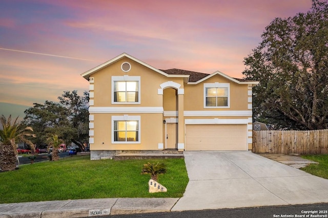 traditional home featuring an attached garage, fence, concrete driveway, stucco siding, and a front lawn