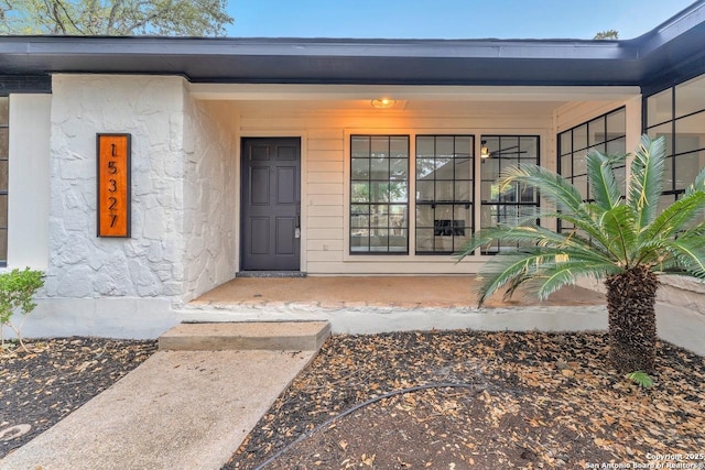 entrance to property with a porch and stucco siding