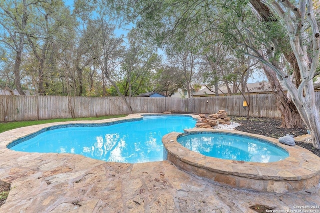 view of swimming pool featuring a patio, a fenced backyard, and a pool with connected hot tub