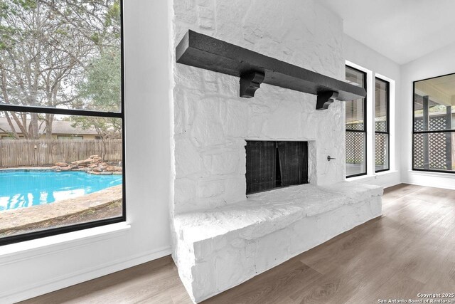 unfurnished living room featuring a fireplace, wood finished floors, and baseboards