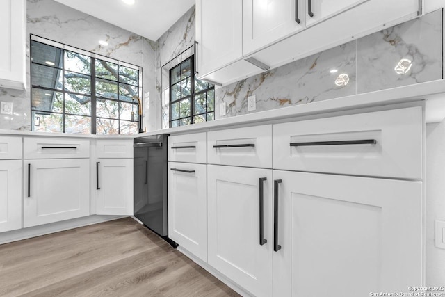 kitchen with light countertops, light wood-type flooring, white cabinetry, and decorative backsplash