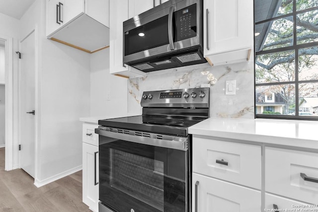 kitchen with stainless steel appliances, light countertops, light wood-style flooring, backsplash, and white cabinetry