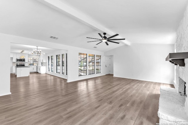 unfurnished living room featuring a large fireplace, visible vents, wood finished floors, vaulted ceiling with beams, and ceiling fan with notable chandelier