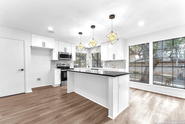 kitchen with white cabinets, visible vents, stainless steel appliances, and wood finished floors