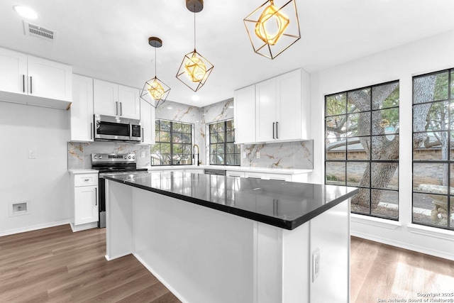 kitchen with dark wood-style floors, white cabinetry, appliances with stainless steel finishes, and decorative backsplash