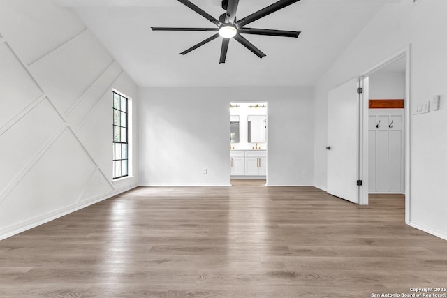 unfurnished living room featuring a ceiling fan, lofted ceiling, light wood-style flooring, and baseboards