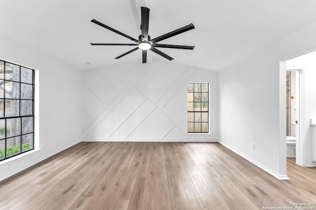 unfurnished room with lofted ceiling, ceiling fan, wood finished floors, and baseboards