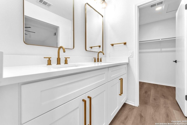 bathroom with wood finished floors, a sink, and visible vents