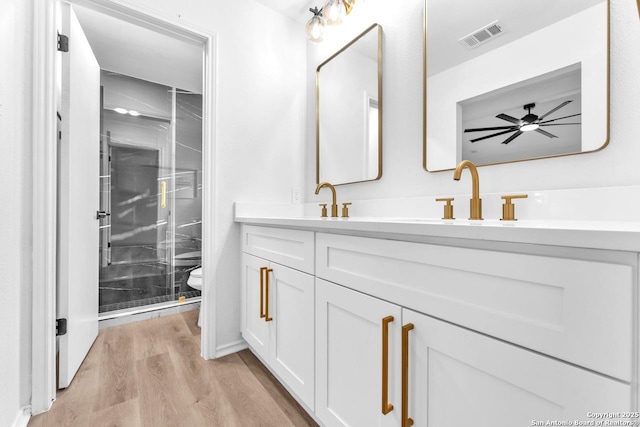 full bath featuring double vanity, visible vents, toilet, wood finished floors, and a shower stall