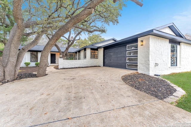 view of front of house with a garage, stone siding, and driveway