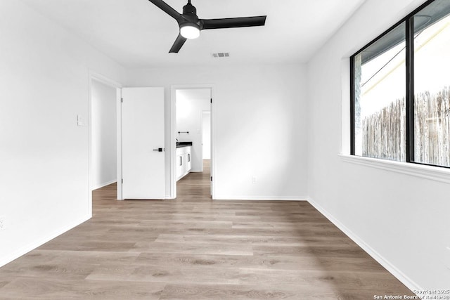 unfurnished bedroom with a ceiling fan, light wood-style flooring, visible vents, and baseboards