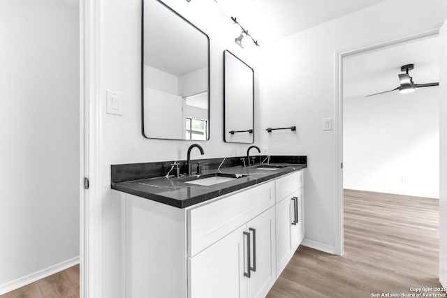 bathroom with ceiling fan, double vanity, wood finished floors, and a sink