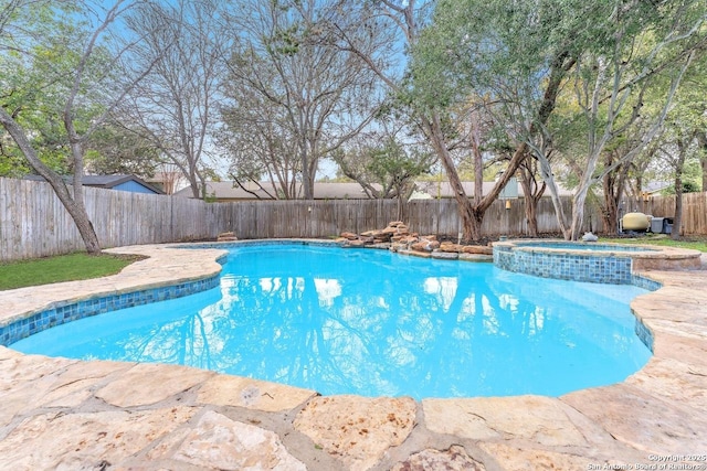 view of pool featuring a pool with connected hot tub and a fenced backyard