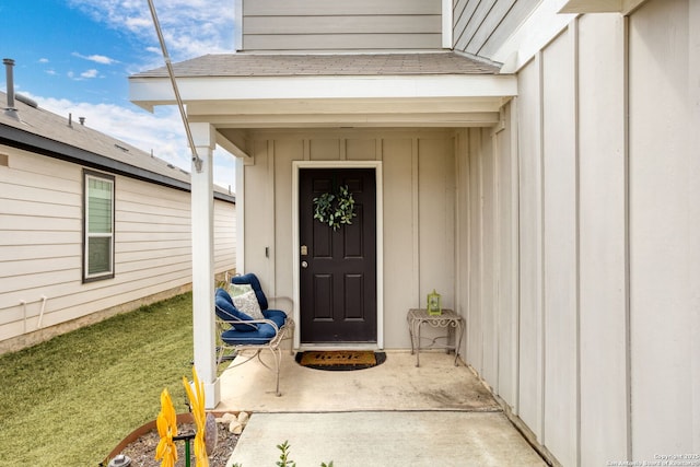 doorway to property with board and batten siding and a shingled roof