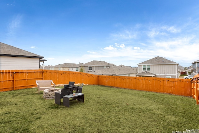 view of yard with a fire pit, a fenced backyard, and a residential view