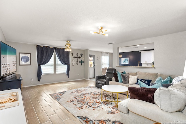 living room with wood finish floors, visible vents, ceiling fan, a textured ceiling, and baseboards