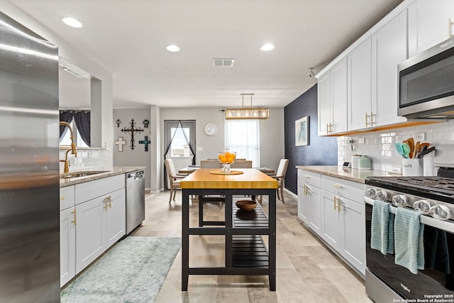 kitchen featuring visible vents, appliances with stainless steel finishes, decorative backsplash, and light stone counters