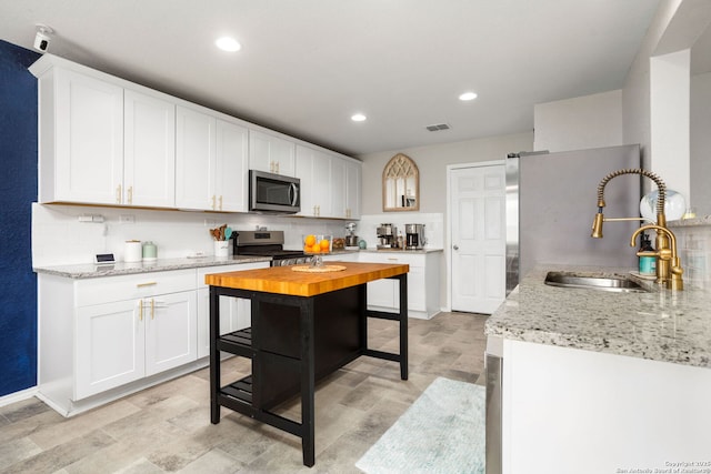 kitchen featuring visible vents, white cabinets, appliances with stainless steel finishes, backsplash, and a sink