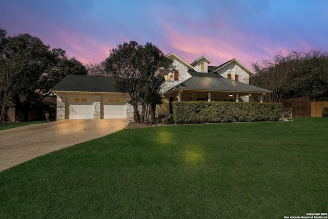 view of front of property featuring fence, a garage, stone siding, driveway, and a front lawn