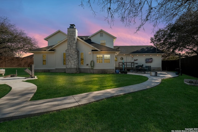 rear view of house with a patio area, a chimney, fence, and a lawn