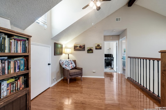 living area with high vaulted ceiling, visible vents, wood finished floors, and beamed ceiling