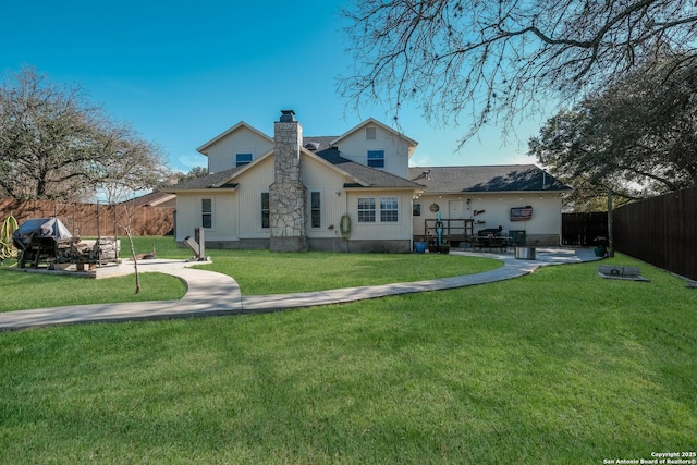 rear view of property featuring a patio, a fenced backyard, a shingled roof, a lawn, and a chimney