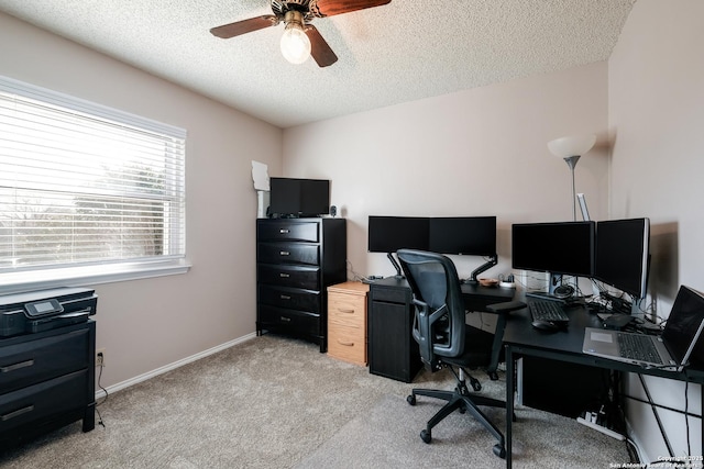 office space featuring light carpet, a textured ceiling, a ceiling fan, and baseboards