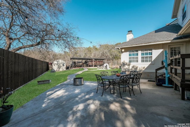 view of patio with entry steps, a fenced backyard, an outbuilding, a shed, and outdoor dining space