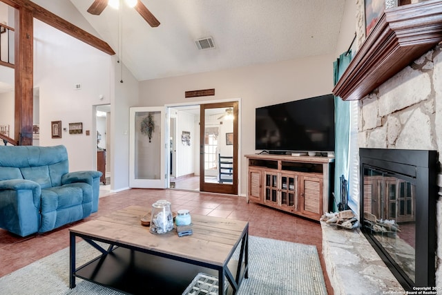 tiled living area featuring visible vents, lofted ceiling, ceiling fan, a textured ceiling, and a fireplace