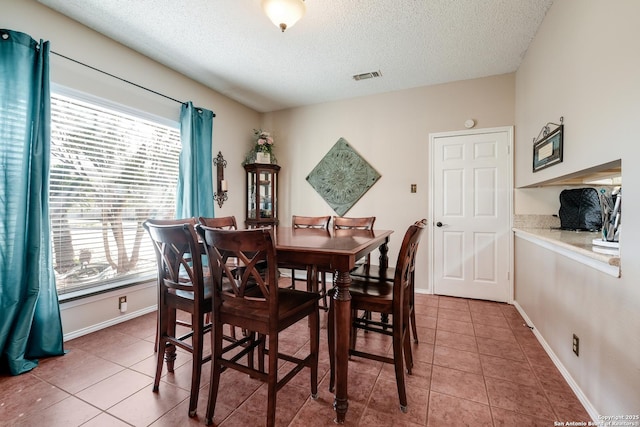 dining room with visible vents, a textured ceiling, baseboards, and light tile patterned floors