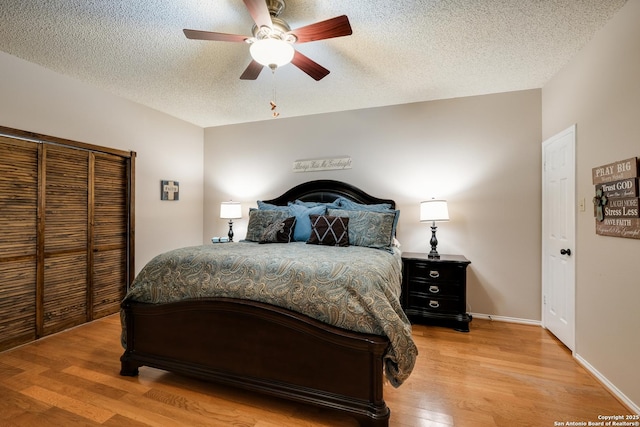 bedroom with a textured ceiling, ceiling fan, light wood-type flooring, and baseboards