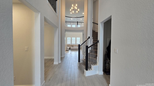 entrance foyer with a chandelier, a high ceiling, wood finished floors, baseboards, and stairs