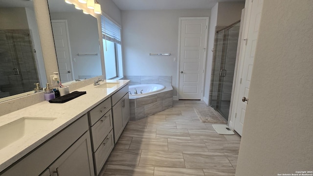 full bathroom with double vanity, a garden tub, a shower stall, and a sink