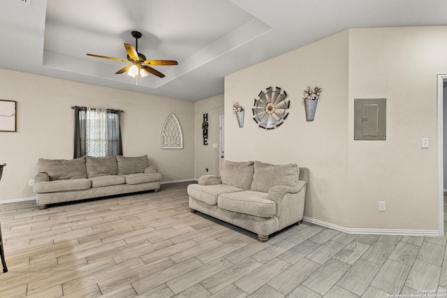 living room with electric panel, baseboards, a ceiling fan, wood tiled floor, and a tray ceiling