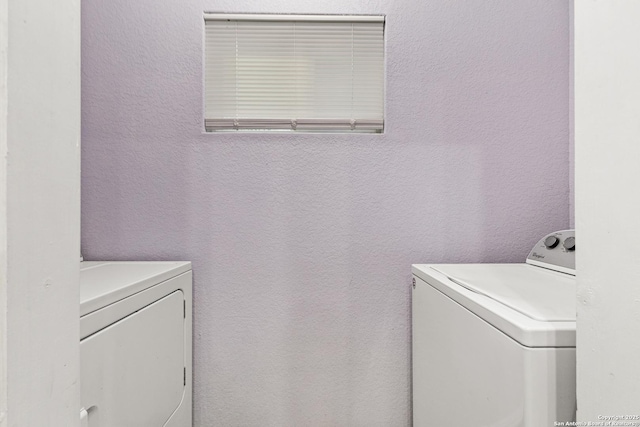 washroom with a textured wall, laundry area, and independent washer and dryer